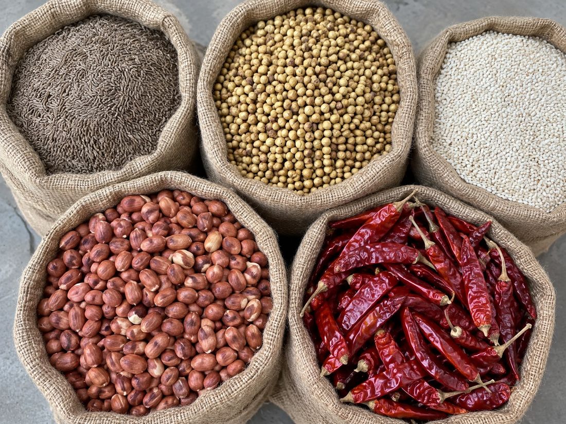 Open jute sacks of cumin, coriander, sesame, groundnut and dried red chillies, seen from above